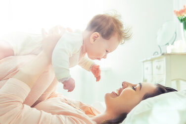 happy family. mother playing with her baby in the bedroom.